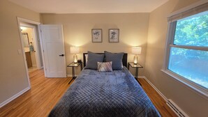 A bedroom with a bed, two bedside lamps, a window with a view, and a door leading to another room. - Spacious 5-bedroom house in Bloomington (Minneapolis)