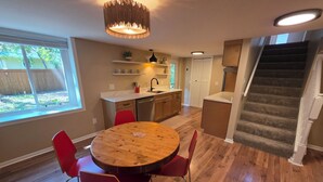 A dining area with a wooden table and red chairs, a kitchen with a sink and cabinets, and a staircase leading to an upper level. - Spacious 5-bedroom house in Bloomington (Minneapolis)