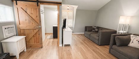 Een loft met een houten deur, een plafondventilator, een bank, een televisie en een lamp.