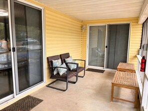 A covered patio with sliding glass doors, a wooden table, and wicker chairs. - Lakeside Escape With Boat Slip (Rocky Mount)