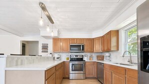 A modern kitchen with wooden cabinets, stainless steel appliances, and pendant lighting. - Lakeside Escape With Boat Slip (Rocky Mount)