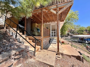 A wooden deck with a railing, a stone staircase, and a view of a lake. - Lakeside Escape With Boat Slip (Rocky Mount)