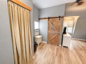 A room with a wooden door, a small white cabinet, a ceiling fan, and a window with blinds. - Lakeside Escape With Boat Slip (Rocky Mount)