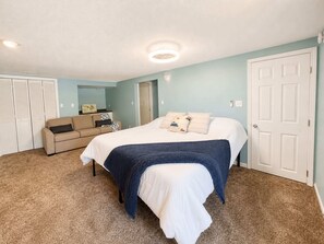 Un dormitorio con cama, sofá, puerta y armario.