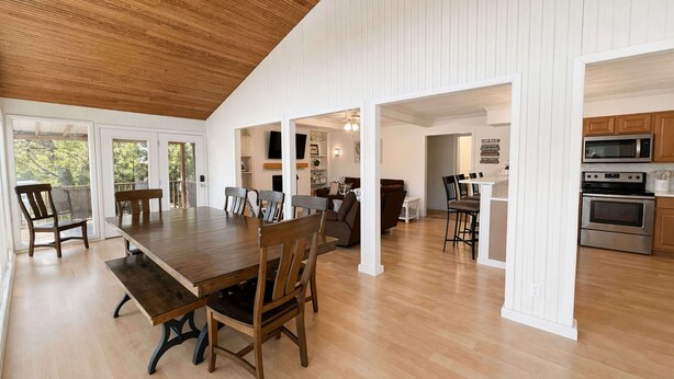 A spacious dining area with a long wooden table and chairs, a kitchen with modern appliances, and a ceiling fan. - Lakeside Escape With Boat Slip (Rocky Mount)