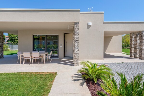 A modern house with a patio, outdoor seating, and a stone pillar.