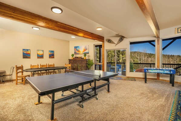 A ping pong table, wooden chairs, a dining table, and artwork on the walls.