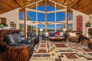A spacious living room with high ceilings, large windows, and a view of the outdoors.