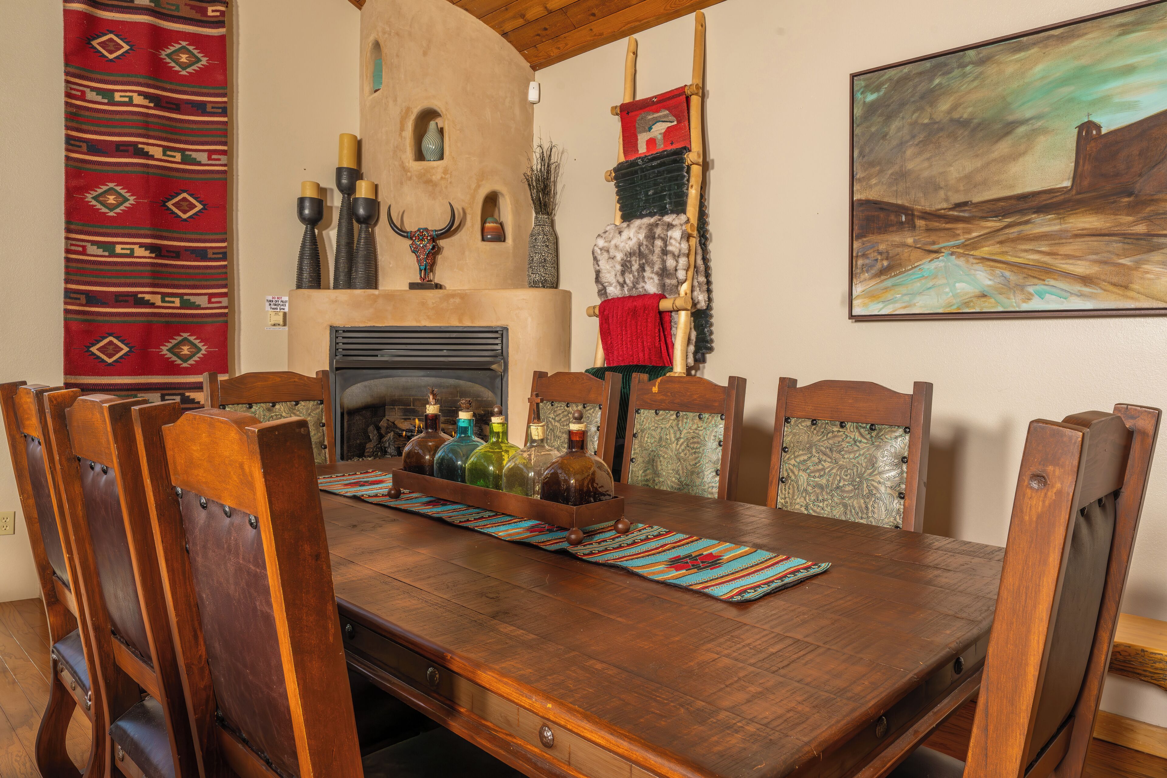 Een houten eettafel met stoelen, een open haard en decoratieve objecten.