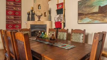 Een houten eettafel met stoelen, een open haard en decoratieve objecten.