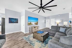 Ein modernes Wohnzimmer mit einem Ecksofa, einem Couchtisch und einem Deckenventilator.