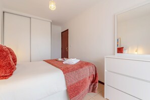 A bedroom with a bed, a dresser, a door, and a mirror. - Bright & Spacious Flat with Balcony by HostWise (Matosinhos)
