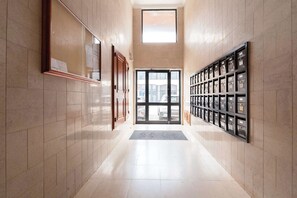 A hallway with a tiled floor, a glass door leading outside, and a row of mailboxes on the right. - Bright & Spacious Flat with Balcony by HostWise (Matosinhos)