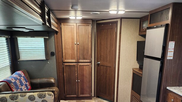 Un intérieur de camping-car compact comprenant un coin cuisine, un espace salon avec un coussin à motifs et un sol carrelé.