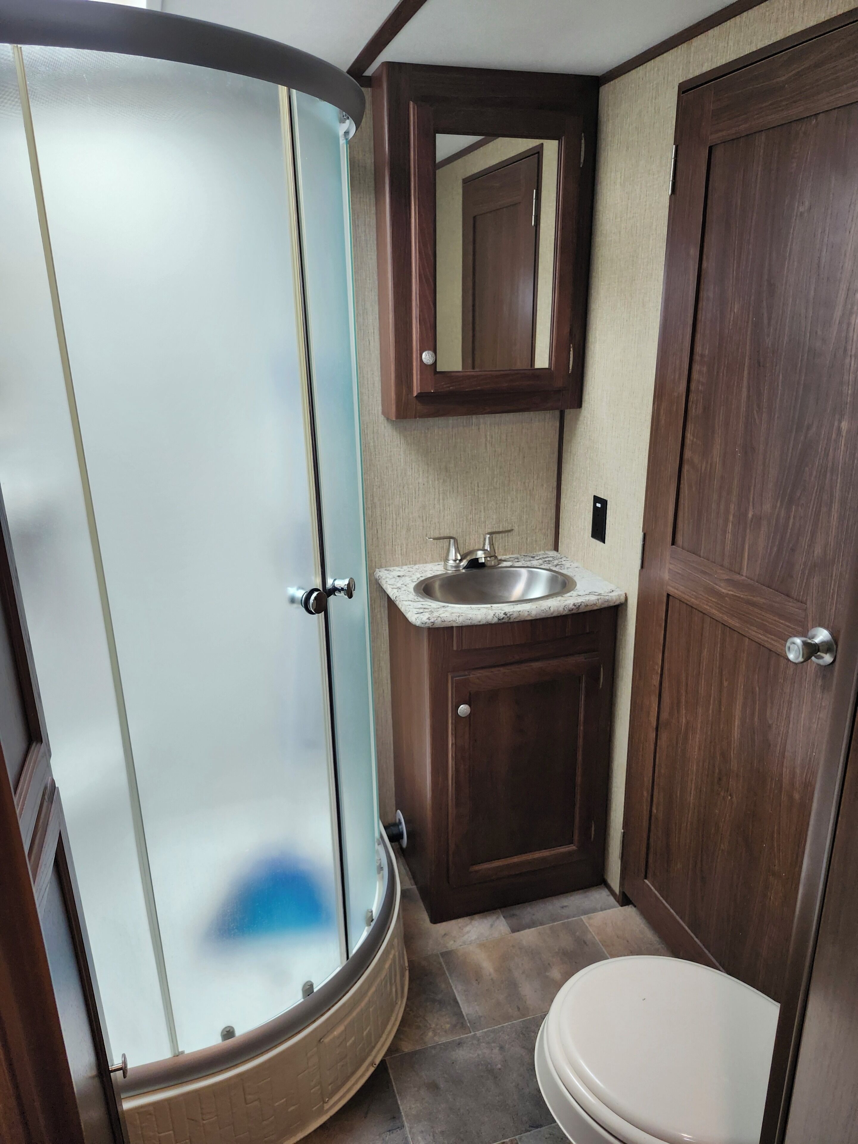 A compact bathroom with a shower, sink, and toilet.