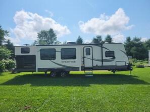 A Sprinter RV parked on a grassy field with a clear sky.