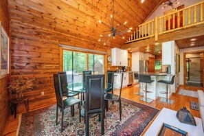 Ein Holzblockhaus-Innenraum mit Essbereich, Küche und einem Balkon.