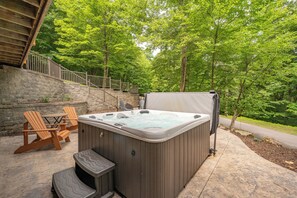Een bubbelbad met een tafel en stoelen, een stenen muur en een trap naar een houten terras.