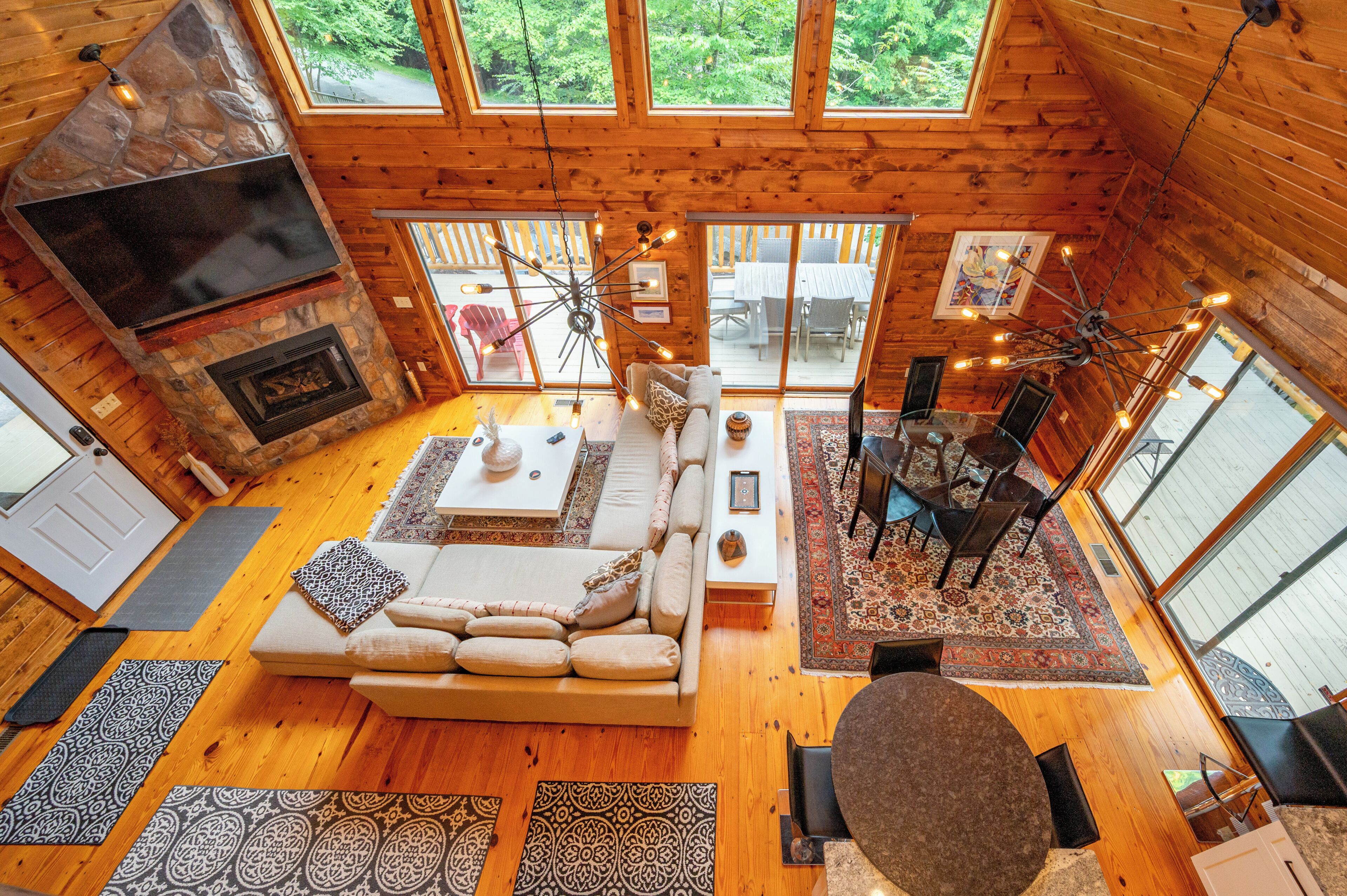 A spacious interior with a stone fireplace, a large sofa, and a dining area with a view of the outdoors.