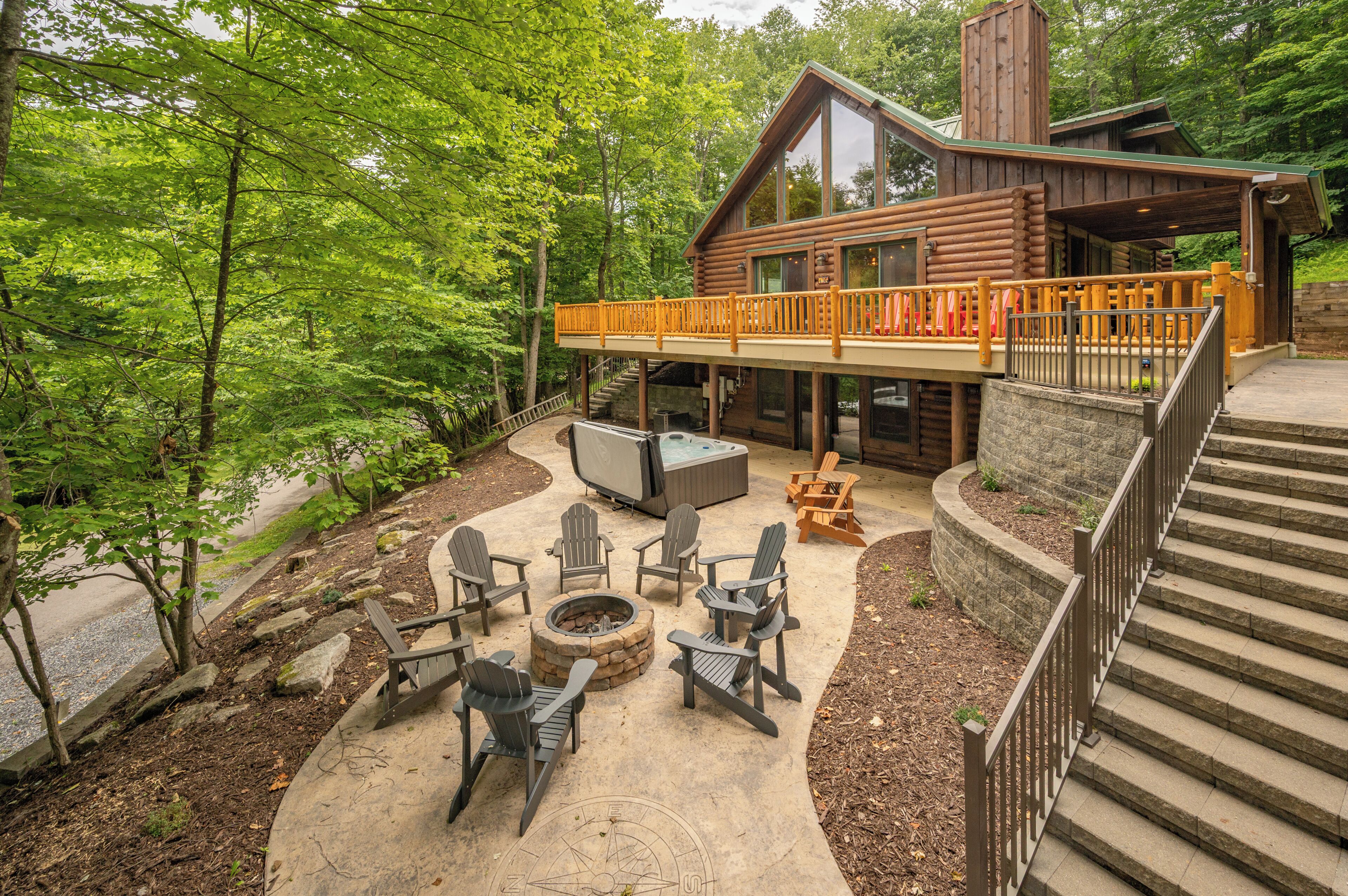 A log cabin with a deck, outdoor seating, a fire pit, and a stone staircase.