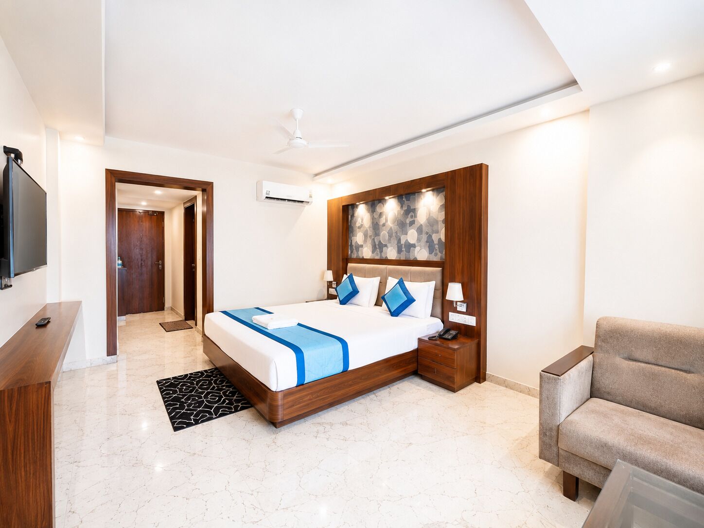 Une chambre d’hôtel moderne équipée d’un grand lit, d’un bureau, d’une télévision et d’un ventilateur de plafond.