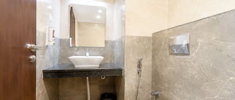 A bathroom with a sink, mirror, shower, and toilet.