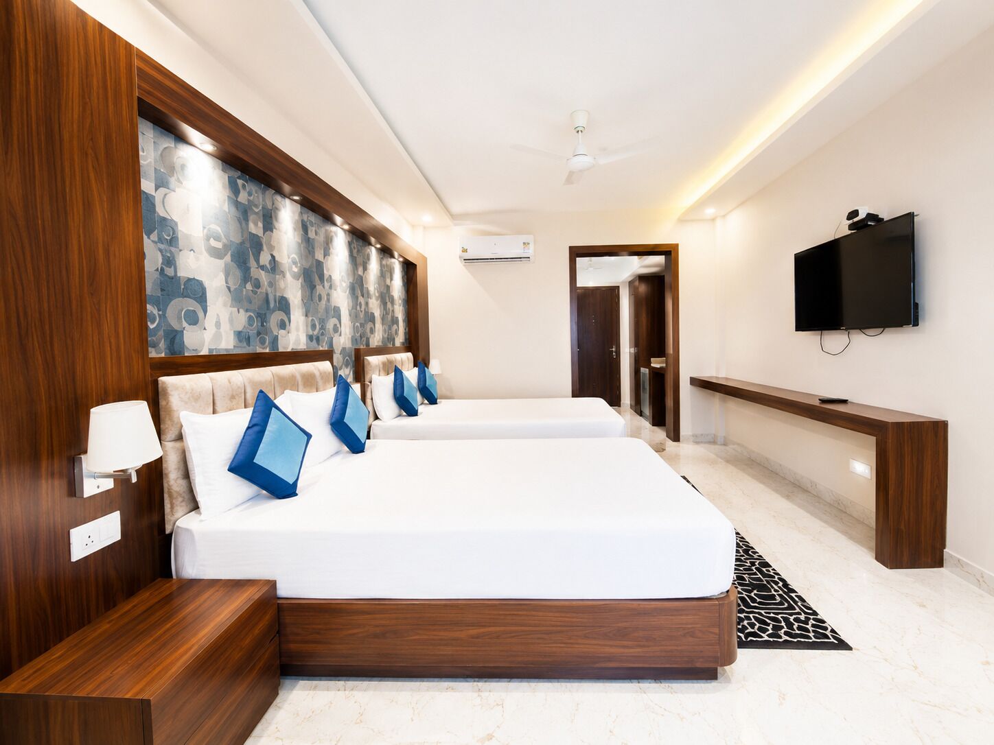 A hotel room with a large bed, bedside tables, a TV, and a bathroom door.