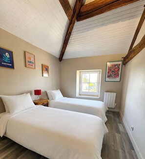 Ein Schlafzimmer mit zwei Betten, einem Fenster und Bildern an den Wänden.