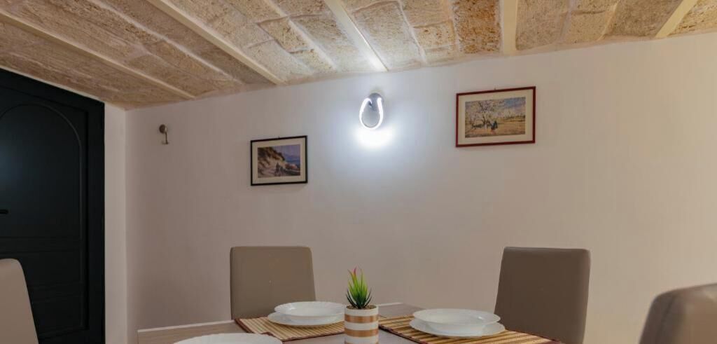 Ein Essbereich mit Tisch für zwei Personen, zwei Stühlen, einer kleinen Pflanzendekoration und gerahmten Bildern an der Wand.