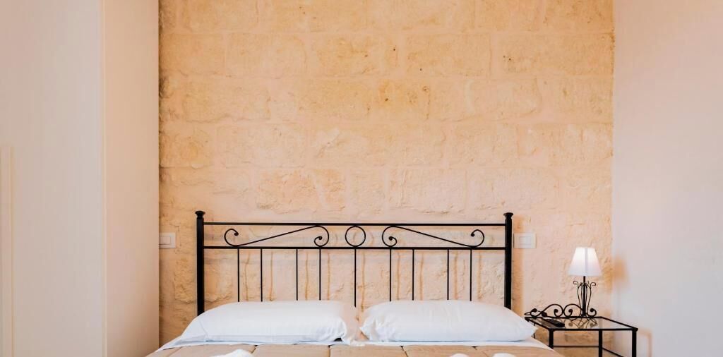 Ein Bett mit Metall-Kopfteil an einer Steinwand.
