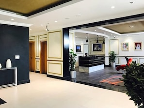 Un vestíbulo de hotel moderno con una recepción, zona de estar y una planta grande.