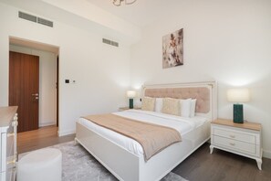 Ein Schlafzimmer mit Bett, Nachttischen, einer Tür und einem Bild an der Wand.