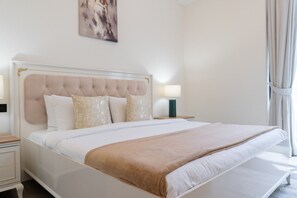 A hotel room with a large bed, a headboard, two bedside tables, and a window with curtains. - Vogue, Wadi Al Safa Villa The Fields Elie Saab (Wadi Al Safa)