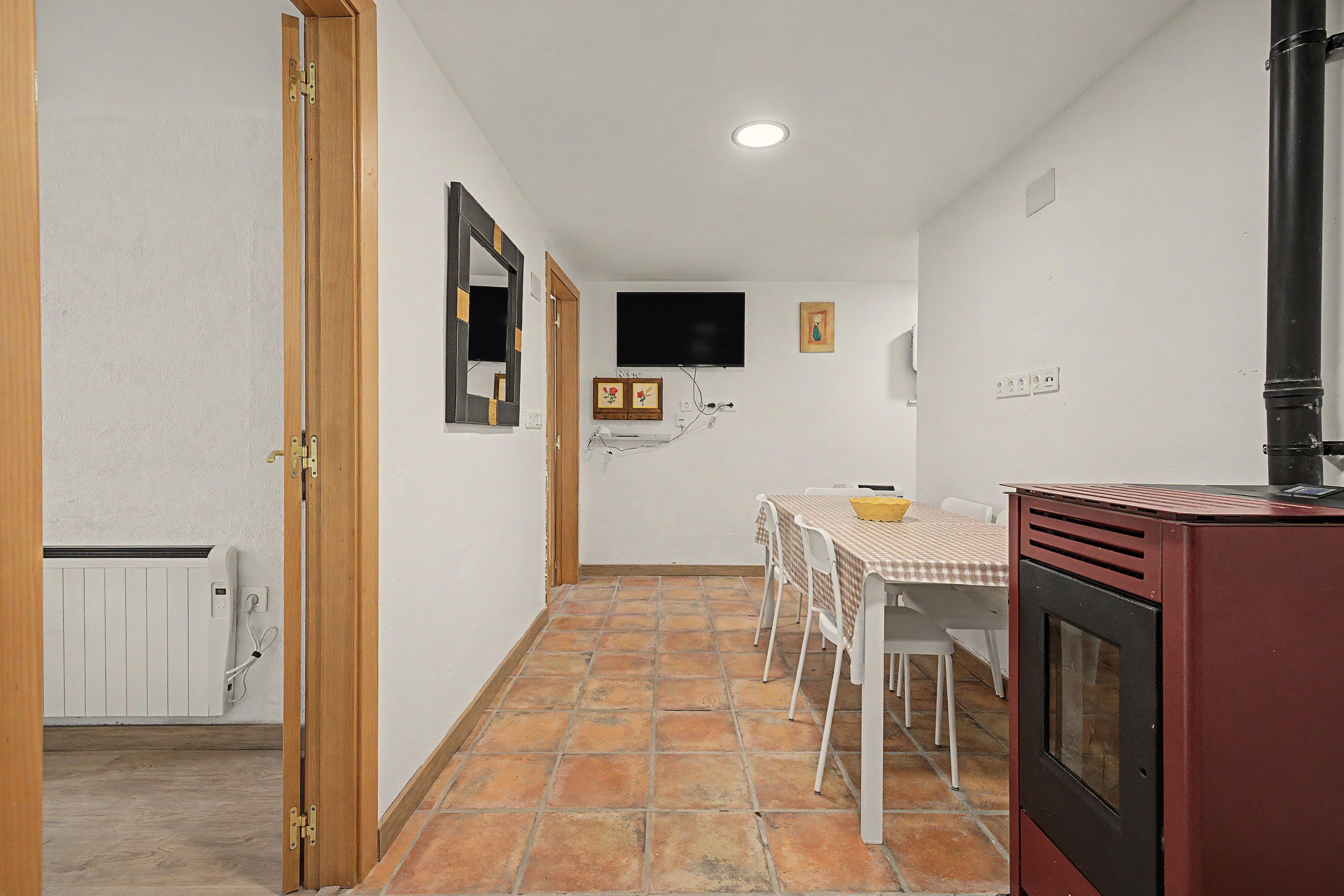 Cozinha compacta com área de refeições, TV fixada na parede e chão em mosaico.