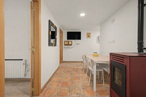 Una cocina compacta con zona de comedor, un televisor montado en la pared y suelo de baldosas.