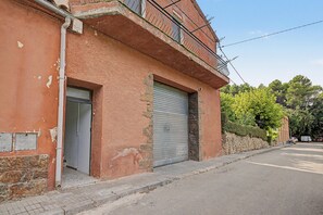 En bygning med lukket metalrullegitter, et lille vindue og et synligt el-skab på siden.