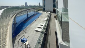 A rooftop swimming pool with lounge chairs, a glass balustrade, and a city skyline view. - Vogue, Arjan Skyz by Danube near Dubai Miracle Garden (Arjan)