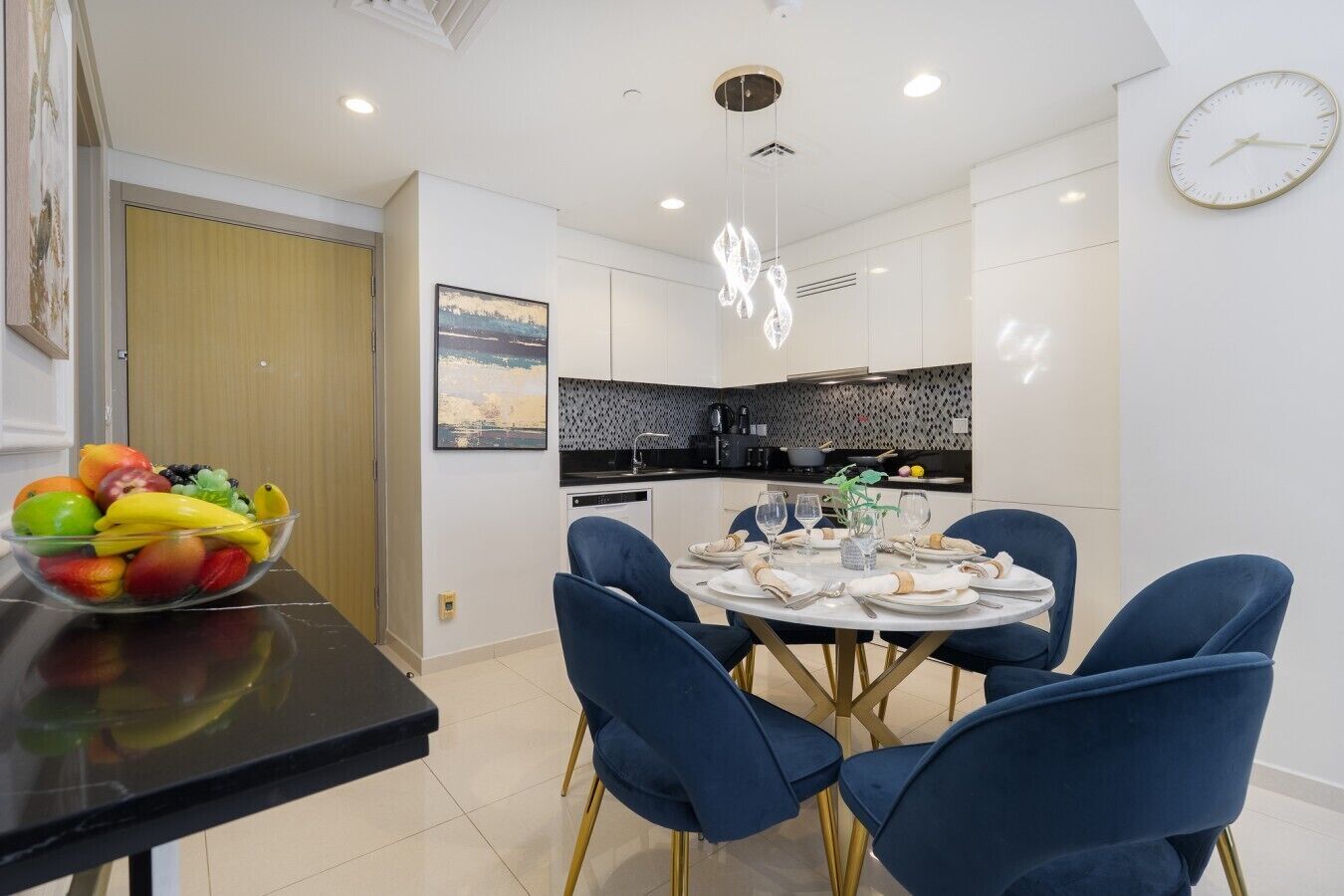 A modern kitchen with white cabinets, a black countertop, and a hanging light fixture.