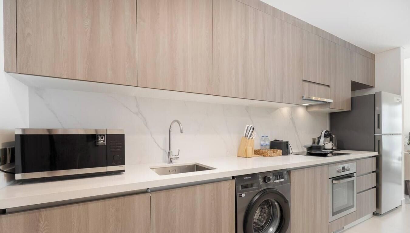 Una cocina moderna con lavadora incorporada, electrodomésticos de acero inoxidable y armarios de madera.