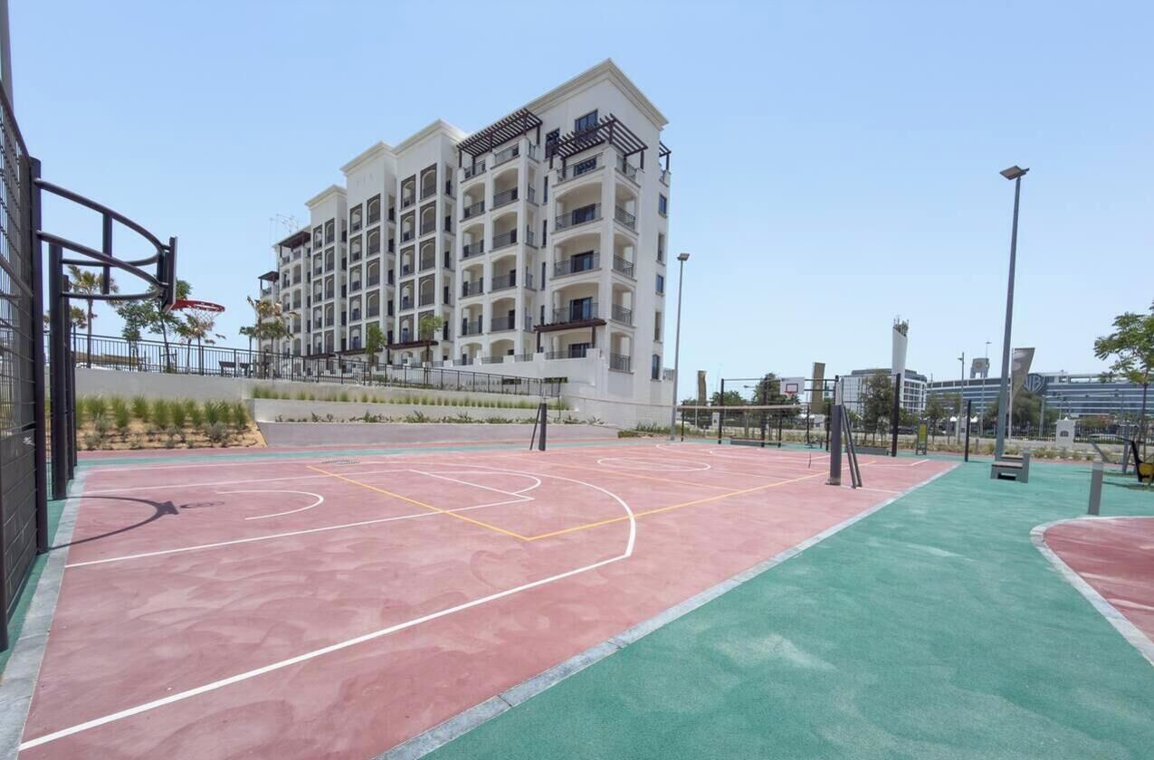 Una cancha de baloncesto al aire libre junto a un edificio residencial de varios pisos.