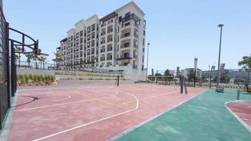Una cancha de baloncesto al aire libre junto a un edificio residencial de varios pisos.