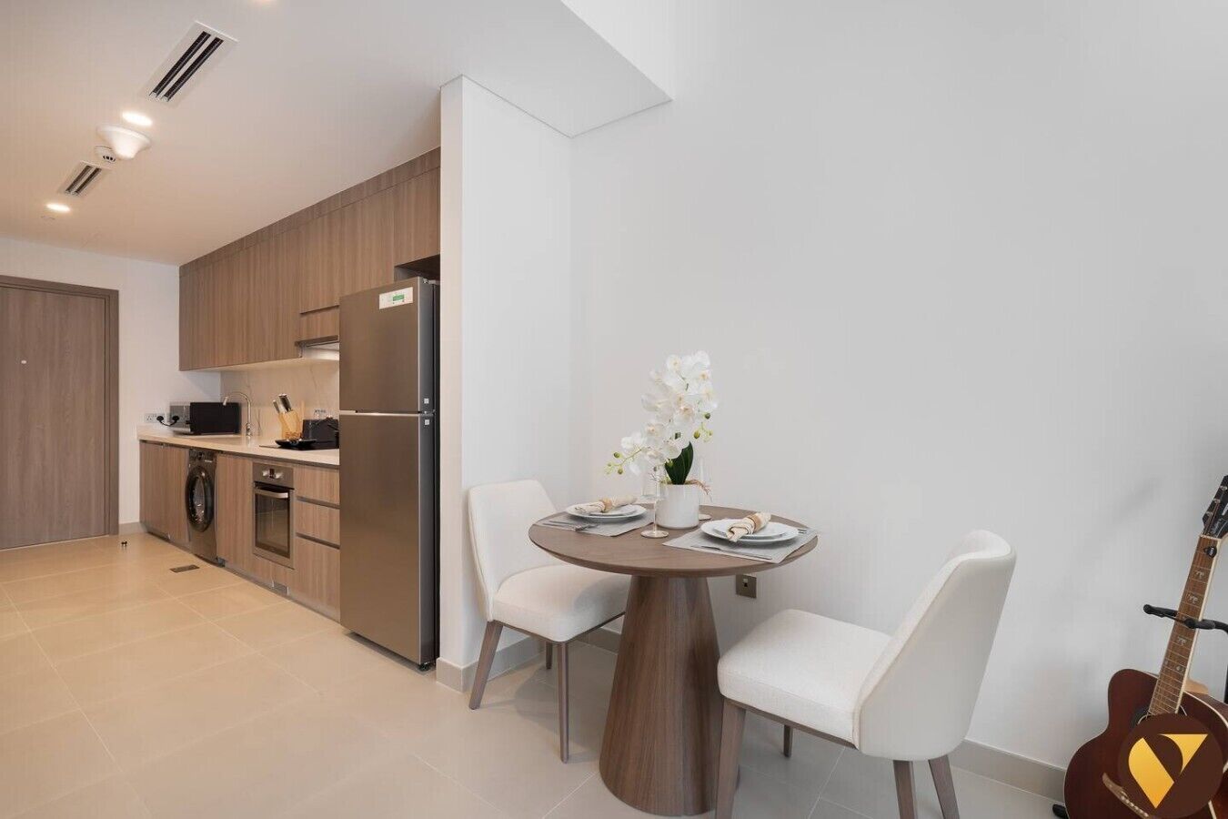 Una cocina moderna con electrodomésticos integrados, una mesa de comedor con sillas y una guitarra.