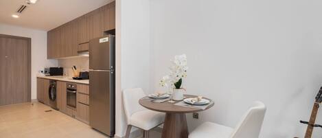 Une cuisine moderne dotée d’appareils électroménagers intégrés, une table à manger avec des chaises et une guitare.