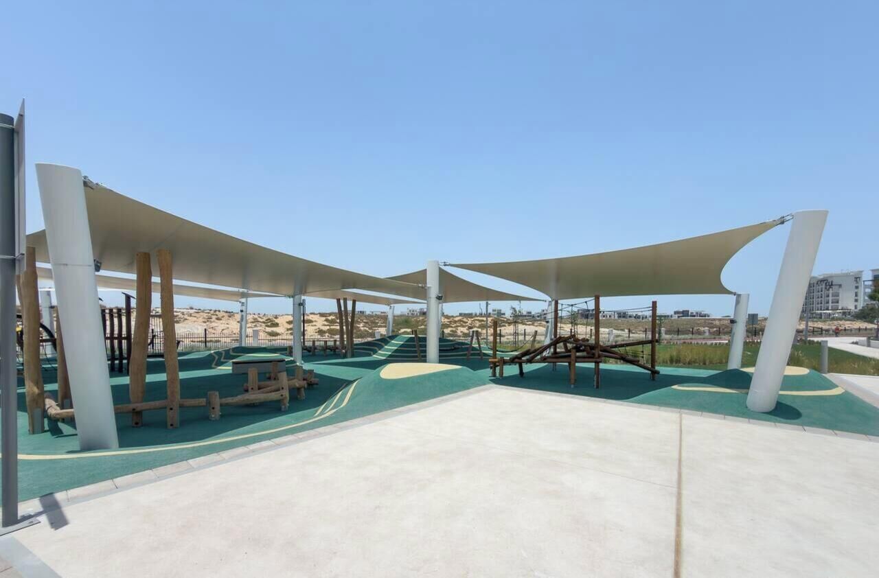 Un patio de juegos al aire libre con estructuras para escalar y zonas con sombra.