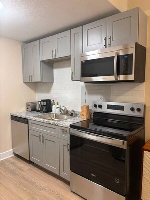 A modern kitchen with grey cabinets, a stainless steel microwave, a built-in oven, and a dishwasher. - 2 Bedroom Poolside Escape Near Austin Hotspots (Austin)
