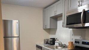 A modern kitchen with stainless steel appliances, grey cabinets, and a wooden floor. - 2 Bedroom Poolside Escape Near Austin Hotspots (Austin)