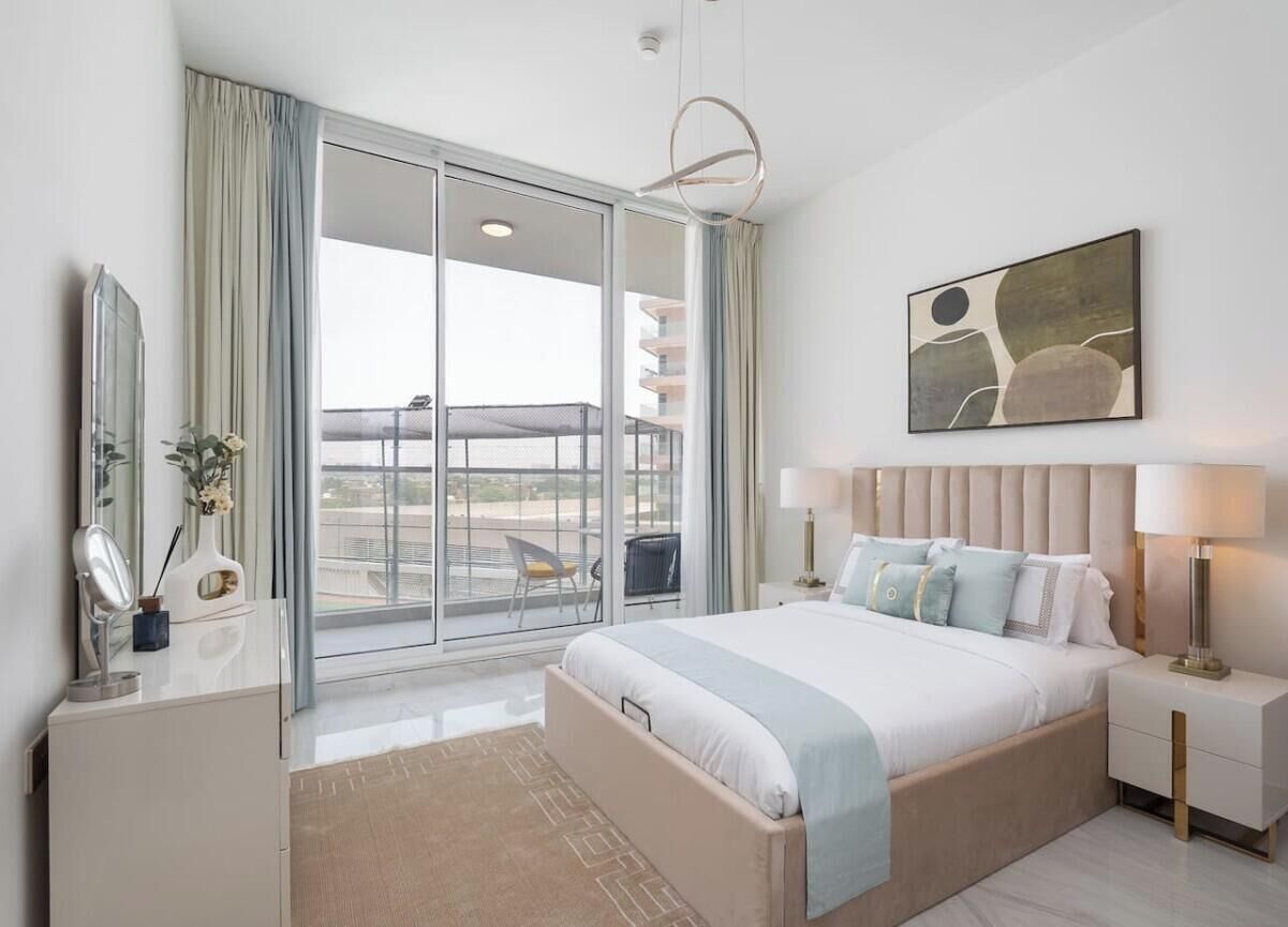 Une chambre d’hôtel avec un grand lit, un balcon avec vue, un lustre moderne et un tableau au mur.