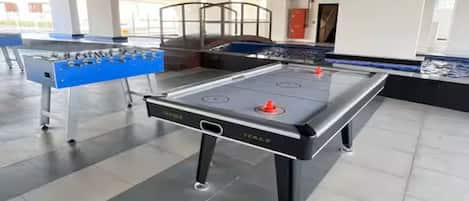 A foosball table in a spacious indoor area with a tiled floor and visible structural elements like beams and columns.
