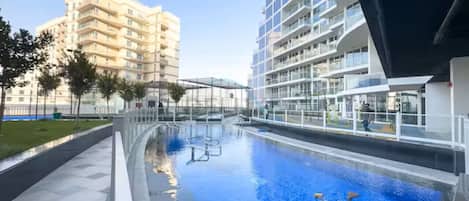 A swimming pool with a clear view of the surrounding buildings and a walkway.