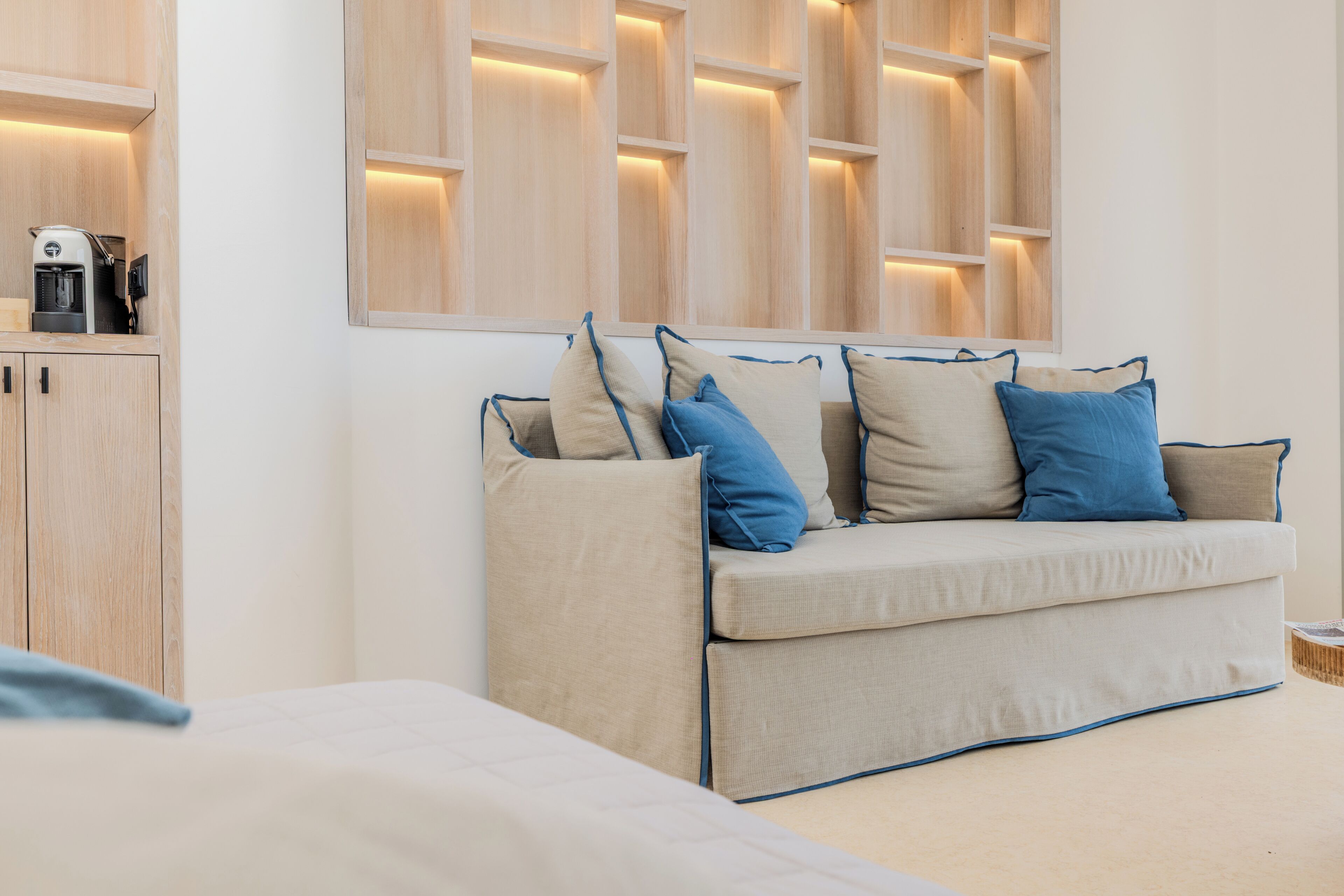 A modern room with a sofa, a coffee machine, and a cabinet.